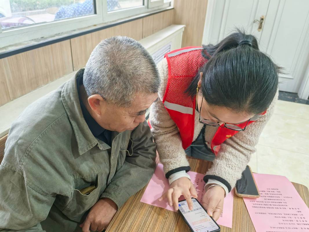 工作人员指导老人使用医保APP